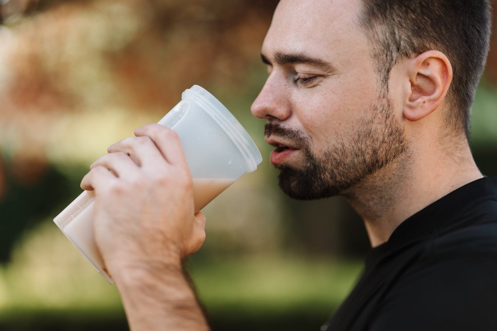 man in black crew neck shirt holding white plastic tumbler