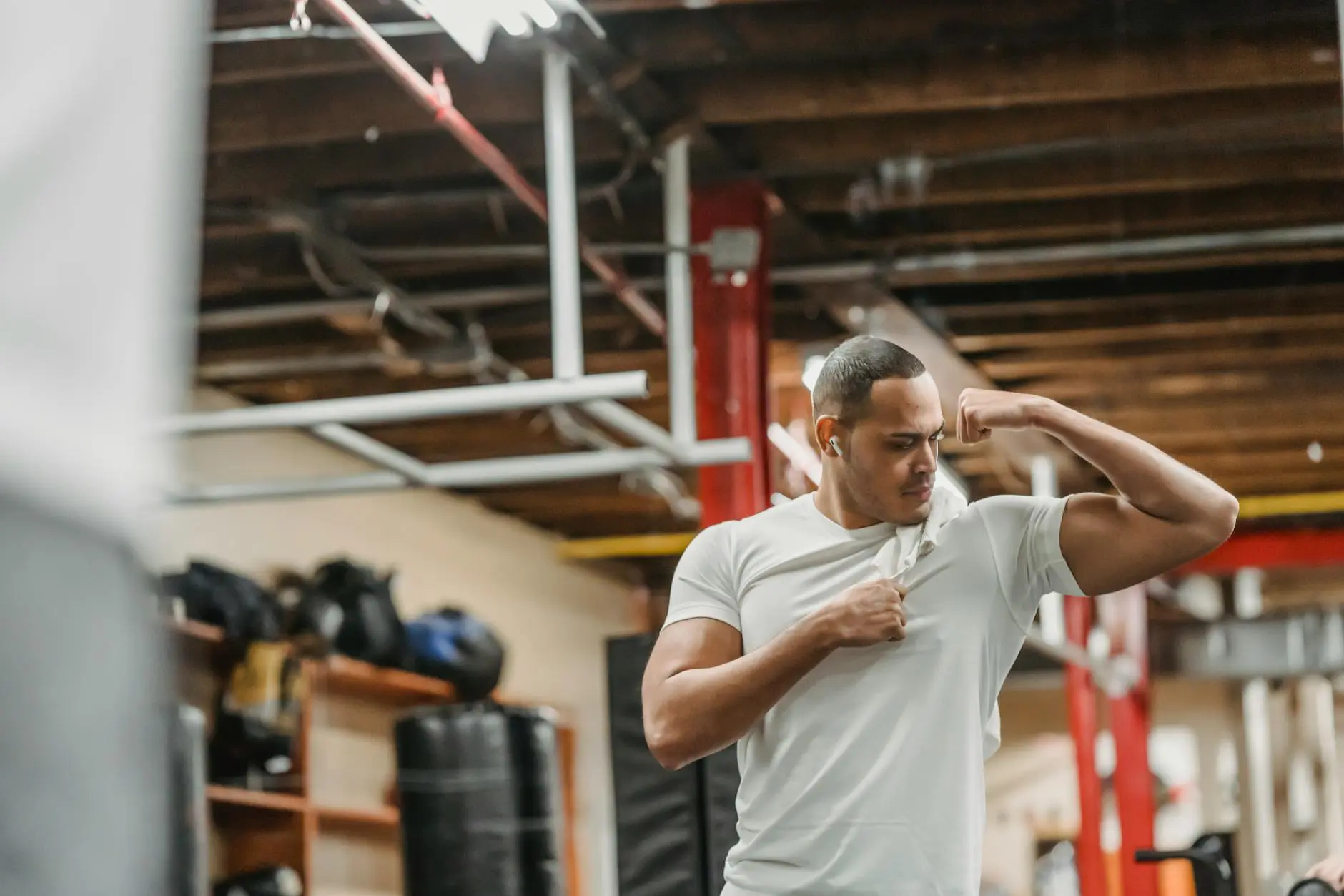 strong ethnic sportsman looking at biceps in gym